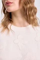 Camiseta de manga corta color crudo con apliques bordados en relieve con forma de flor en toda la prenda.