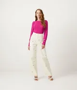 Blusa de punto fucsia con cuello redondo y manga larga abullonada. Tiene botones en forma de corazón en los puños y ondas en el bajo.