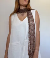 Bufanda tejida artesanalmente con hilado fantasía en tonos marrón, naranja y blanco.