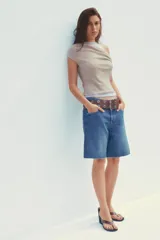 Camiseta blanca con musculosa gris superpuesta con escote asimétrico.