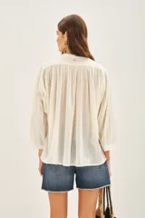 Camisa amarilla de algodón con corte amplio, cuello redondo y mangas 3/4 con puños elásticos.