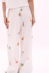 Pantalón blanco de corte amplio con estampado de motivos marinos y cintura elástica con cinturón azul con la inscripción 'Verano Mirando al Mar'.
