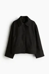 Campera corta negra de tejido de fieltro suave con cuello clásico y cierre frontal con botones. Modelo de corte holgado con hombros caídos y bolsillos insertados adelante.