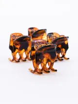 Set de cuatro pinzas pequeñas de plástico negro para el pelo.