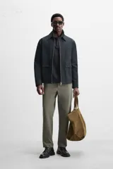 Pantalón chino negro slim fit confeccionado en tejido técnico de secado rápido. Cuenta con bolsillos frontales y traseros de vivo. Cierre frontal con cremallera y botón.
