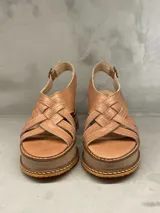 Sandalias de cuero color beige con plataforma de madera y suela de goma. Tiras anchas cruzadas en el empeine y tira con hebilla al tobillo.