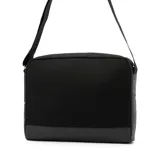 Bolso tipo mensajero o bandolera de color negro, con cuerpo principal de tela y base de material sintético liso. Presenta un bolsillo frontal con cierre metálico y un parche pequeño con el logo de Calvin Klein. Incluye una correa ajustable de tela negra.