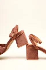 Sandalia de terciopelo verde con taco cuadrado de 7 cm, punta cuadrada y tiras anchas anudadas en el empeine. Cuenta con una tira fina ajustable al tobillo con hebilla dorada.