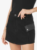 Minifalda negra de sarga de algodón, con cintura alta, pretina con trabillas, dos bolsillos cargo laterales con solapas abotonadas, aberturas delanteras y traseras, cierre frontal con cremallera y botón, y etiqueta de la marca en la espalda.