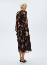 Vestido midi de gasa color negro con estampado floral en tonos rojos, rosados y verdes. Tiene escote en V, mangas largas abullonadas y corte evasé.