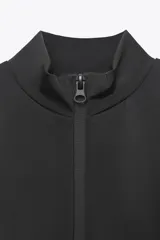 Chaqueta negra entallada de cuello alto y manga larga con cierre frontal de cremallera termosellada.