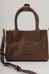 Cartera pequeña de cuero marrón oscuro, con asas superiores y cierre de cremallera lateral visible. Presenta el logo de la marca grabado en el frente.