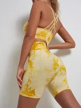 Conjunto deportivo color amarillo con estampado abstracto, compuesto por un top con tirantes cruzados en la espalda y un short de ciclista.