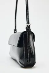 Bolso de hombro negro acharolado con solapa y asa ajustable. Cierre con imán.
