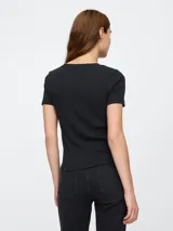 Remera de mujer color crema, de corte ajustado, con cuello redondo y logo de la marca bordado en el pecho.