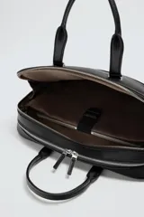 Maletín negro con acabado texturizado, compartimento principal con cierre de cremallera, bolsillo interior con cremallera, bolsillo frontal con cremallera, bolsillo trasero para dispositivos electrónicos de hasta 13 pulgadas y bolsillo trasero con cremallera. Tiene dos asas de mano y un asa de hombro ajustable y extraíble.