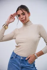 Polera de punto acanalado color beige, con cuello alto y mangas largas.