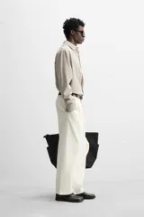 Camisa color crema de corte relaxed fit, confeccionada en tejido de mezcla de algodón suave al tacto. Tiene cuello solapa, manga larga con puños abotonados, un bolsillo de parche en el pecho y cierre frontal con botones.
