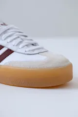 Zapatillas Adidas Samba de cuero blanco con puntera de gamuza gris y tres tiras de cuero bordó. Suela de goma color caramelo traslúcida.