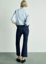 Jeans de tiro alto color azul oscuro, corte cropped y acampanado, con cinco bolsillos y cierre de cremallera y botón.