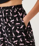 Short runner negro con estampado de lombrices rosas y cuadrillé blanco, de cintura media con elástico.