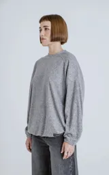 Sweater gris jaspeado de manga larga y cuello redondo, con elástico ajustable en el ruedo inferior.