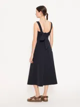 Vestido midi rojo de poplin con lycra, corte evasé, breteles anchos, bolsillos laterales y tajo frontal. Se ajusta en la espalda con un lazo.