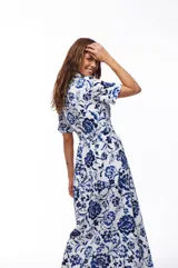 Vestido midi de algodón con estampado floral en tonos azul y blanco, corte camisero, cuello clásico, mangas cortas y cinturón con hebilla redonda de madera.