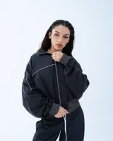 Campera deportiva bomber negra con recortes y vivos blancos.