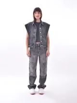 Chaleco de denim azul lavado, sin mangas, con cuello camisero, botones frontales y bolsillos de parche en el pecho.