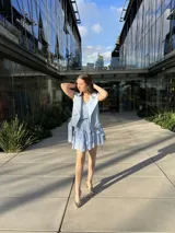 Chaleco blanco de cuero sintético con cierre cruzado, cuello solapa y cinturón con hebilla.