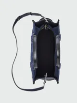 Bolso tote mediano Marc Jacobs The Suede Leather Blocked, color azul marino, confeccionado en gamuza con detalles y asas en cuero liso negro. Presenta un compartimento principal con cierre superior y correa ajustable y desmontable para llevar al hombro o cruzado.