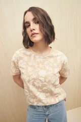 Remera color beige con estampado floral blanco, de manga corta y corte clásico.