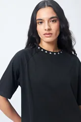 Remera negra de corte holgado con mangas ranglan y cuello redondo con bordado de estrellas blancas.