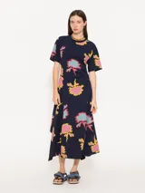 Vestido midi de algodón con estampado floral multicolor, cuello redondo y mangas cortas. Presenta un corte asimétrico con frunces en la cintura.