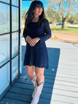 Vestido corto azul tejido a crochet, con mangas largas caladas y forro de algodón.
