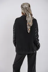 Campera de jean negra con tachas metálicas, diseño oversize y cierre frontal.
