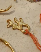 Collar con dije de bronce macizo con forma orgánica o de coral, suspendido de un hilo de seda natural color naranja.