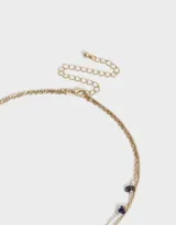 Collar corto dorado de doble cadena, una con piedras amatistas y otra con dije de corazón relicario.