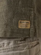 Camisa color verde militar de manga larga con cuello clásico, cierre frontal con botones y dos bolsillos de parche en el pecho.