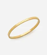 Pulsera tipo brazalete rígido de metal, color dorado, con textura acanalada compuesta por pequeños bloques cuadrados en relieve a lo largo de toda su circunferencia.