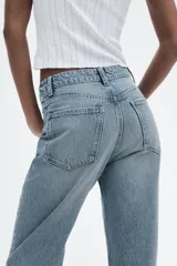 Pantalón de jean negro de tiro alto, corte recto, con cinco bolsillos y cierre frontal con cremallera y botón metálico.