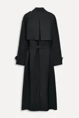 Trench negro oversize con cuello solapa, manga larga con trabilla y botón, bolsillos delanteros, cinturón ajustable con lazadas, abertura en la espalda y cierre frontal con botones ocultos por solapa.