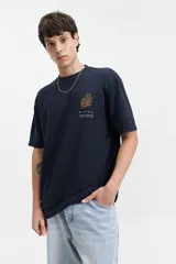 Remera beige de manga corta con textura y corte oversize. Presenta un pequeño bordado en relieve en el pecho.