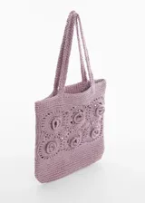 Bolso de mano tipo tote bag color lila, tejido a croché con diseño de flores en relieve.