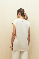 Chaleco color crudo de tejido de punto con cuello redondo y sisas amplias. Tiene corte recto con aberturas laterales en el ruedo.