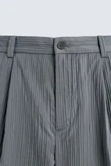 Pantalón cargo gris con textura acanalada, corte relaxed fit, cintura elástica con pliegues frontales, bolsillos laterales tipo cargo con solapa, bolsillos frontales y traseros de vivo, cierre frontal con cremallera y botón.