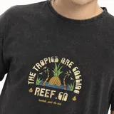 Remera negra de corte oversize con estampado de palmeras y piñas.