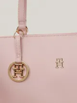 Bolso tipo tote color rosa pálido, con doble asa de hombro y cierre superior con cremallera. Incluye un dije colgante con el logo de la marca y el logo metálico en la parte frontal.