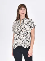 Camisa de manga corta con estampado animal print en tonos beige, marrón y negro. Tiene cuello mao y cierre frontal con botones.
